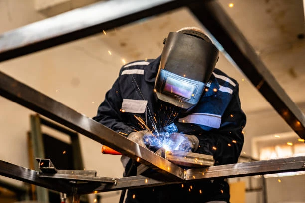 Welder in a protective mask working on metal fabrication